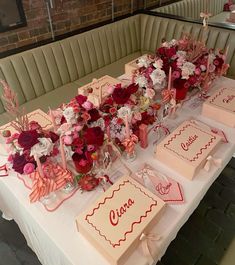 a table set up with pink and red flowers, cards, candles and place settings