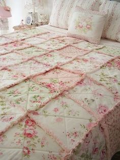 a bed with pink flowers on it and white sheets, pillows, and pillowcases