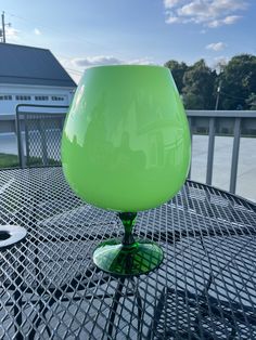 a green glass sitting on top of a metal table