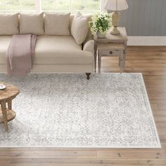 a living room with a couch, coffee table and rug on the floor in front of a window