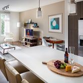 an open kitchen and living room are shown in this image, with white counter tops