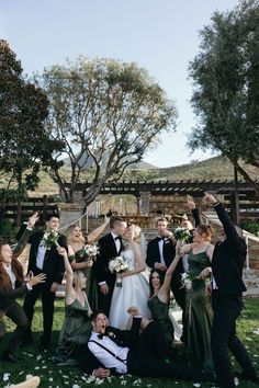 a group of people standing and sitting on top of a grass covered field next to each other