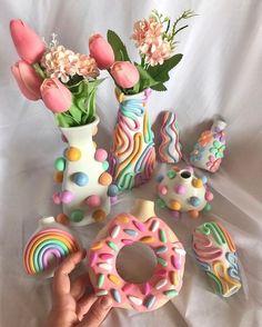 a hand holding a doughnut next to vases with flowers and other decorative items