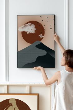 a woman is pointing at a painting on the wall