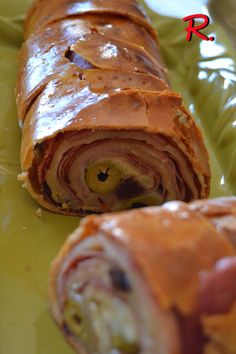 a green plate topped with a roll covered in meat and cheese next to a slice of pizza