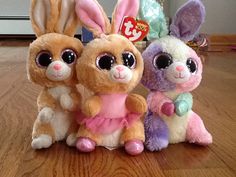 three stuffed animals sitting on top of a wooden floor