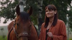 a woman standing next to a brown horse