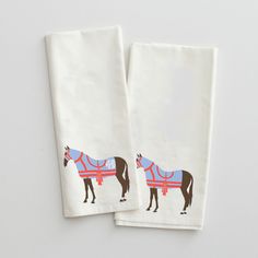 two tea towels with horses on them sitting next to each other in front of a white wall