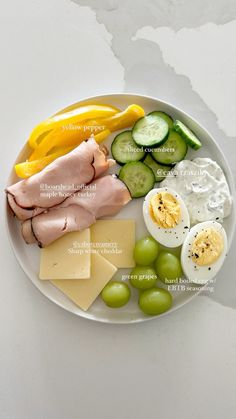 a white plate topped with meat, cheese and veggies next to an egg