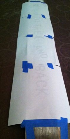 a piece of paper taped to the side of a toilet paper roll with blue tape on it