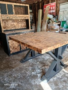 a wooden table with metal legs in a room filled with furniture and other pieces of wood