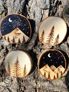 four wood slices with trees painted on them