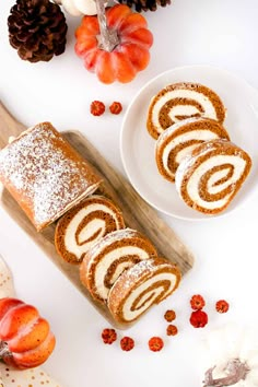 slices of cinnamon roll sitting on top of a wooden cutting board next to pumpkins