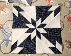 a blue and white quilt on top of a table with bicycles in the back ground