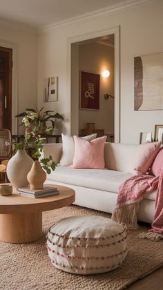 a living room with white couches and pink pillows on top of the rugs