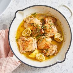 chicken with lemons and onions in a skillet on a white countertop, ready to be eaten