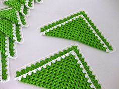 four green and white crocheted coasters sitting next to each other on a table