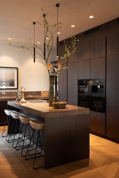 a modern kitchen with an island counter and bar stools, surrounded by dark wood cabinets