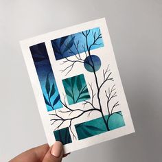 a hand holding up a piece of paper with blue and green art work on it