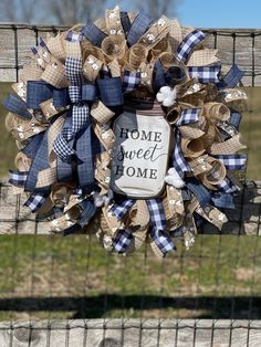 a blue and white wreath with the words home sweet home hanging on a wooden fence