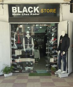 two mannequins in front of a black store with white walls and windows