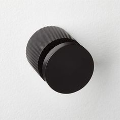 a black knob on the side of a white wall