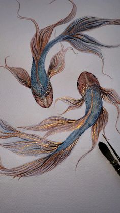 two gold and blue fish with long hair