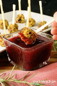 a person dipping something into a small bowl with toothpicks sticking out of it