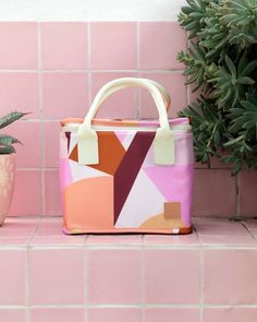 a pink bag sitting on top of a tiled counter next to a potted plant