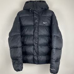 Stay warm during the colder months with this Nike Life Therma-FIT men's puffer jacket. The jacket features a full zip closure and hood to keep you protected from the elements, while the insulated ecodown provides extra warmth. The black solid color and Nike logo accents make this jacket a stylish addition to any wardrobe, perfect for casual wear or outdoor activities like walking, hiking, hunting, skiing, or hockey. Made with polyester outer shell material and lined with polyester, this machine Nike Down Outerwear For Fall, Nike Winter Down Outerwear, Nike Outerwear With Detachable Hood For Cold Weather, Nike Fall Puffer Jacket With Detachable Hood, Nike Winter Outerwear With Pockets, Nike Hooded Down Outerwear, Nike Puffer Jacket With Detachable Hood For Streetwear, Nike Hooded Sport Coat For Winter, Nike Puffer Jacket For Cold Weather With Pockets