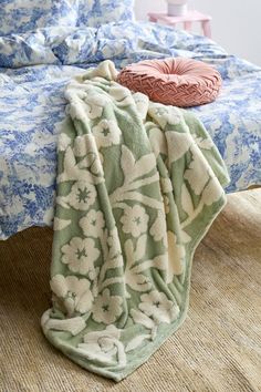 a bed with blue and white bedspread next to a pillow on the floor