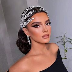 a woman in a black dress wearing a headpiece with crystal stones on the side