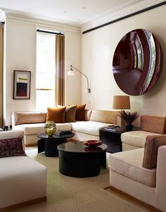 a living room filled with furniture and a large circular mirror on the wall above it