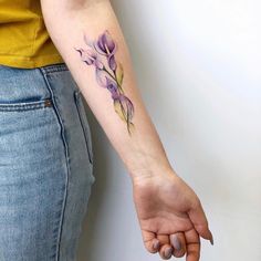 a woman's arm with a purple flower tattoo on it