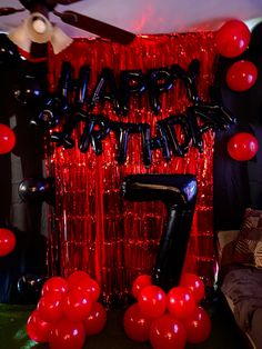 balloons and streamers decorate the entrance to a party with black, red and silver decorations