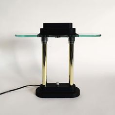 a glass and metal table lamp with a black base on a white background, the light is turned off