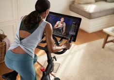 a woman on a stationary exercise bike looking at her computer screen while she is exercising