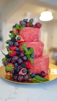 a cake made out of watermelon, grapes and strawberries on a gold plate