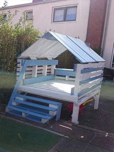 a house made out of pallets sitting on the side of a road in front of a building