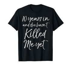 a black shirt that says 10 years in and she hasn't killed me yet