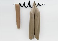 two pieces of cloth hanging from hooks on a white wall with black cords attached to them