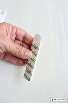 a person is holding a tape on top of a white table with a remote control in their hand