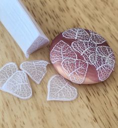 three pieces of lace sitting on top of a wooden table next to a piece of paper