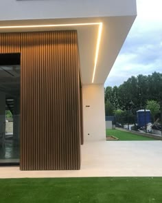 the entrance to a modern house with wooden slats on the outside and grass in front