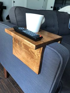 a remote control sitting on top of a wooden table next to a cup of coffee