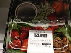 a plastic container filled with lots of different types of fruits and vegetables next to a label that says deli