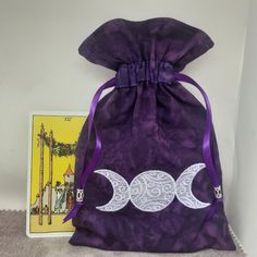 a drawstring bag with two moon designs on it next to a tarot card