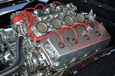 the engine compartment of an old car with red wires attached to it's front end