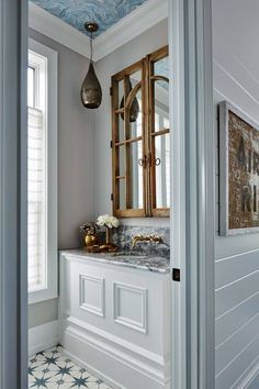 a bathroom with marble counter tops and gold accents on the mirror, along with white cabinets