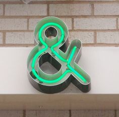 a neon green amp and sign on the side of a brick building with white trim